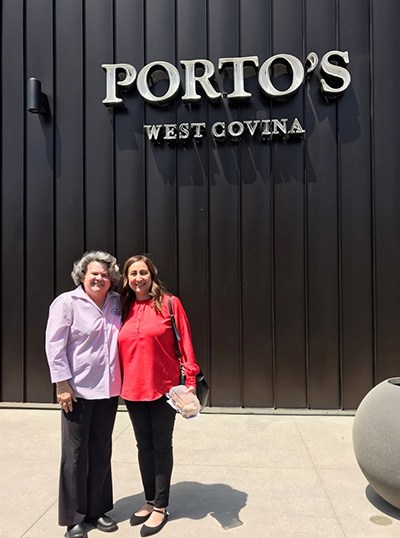 Two people standing in front of a Portos building sign.