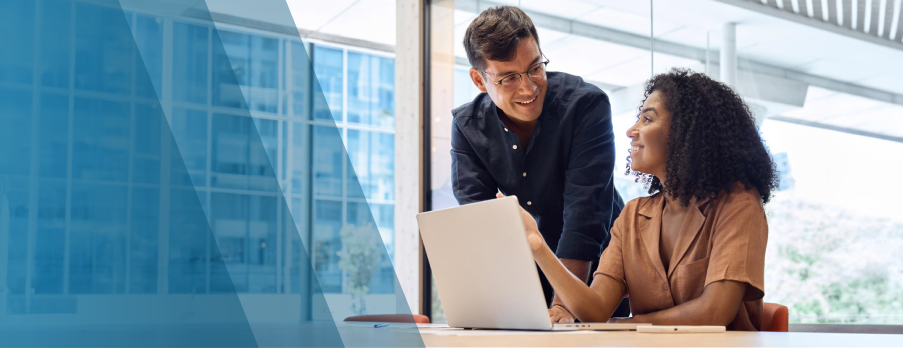 A man and woman are seated together, focused on a laptop screen, engaged in discussion or collaboration.