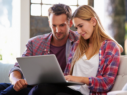 Image of  Man and woman happily working on their laptops in kitchen