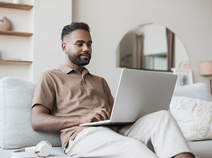 Man sitting on the couch typing on his laptop