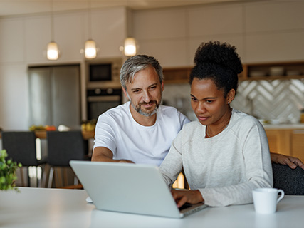 Man and woman happily working on their laptops in kitchen