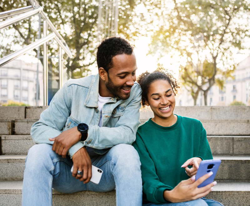Man and young woman smiling looking at a cell phone