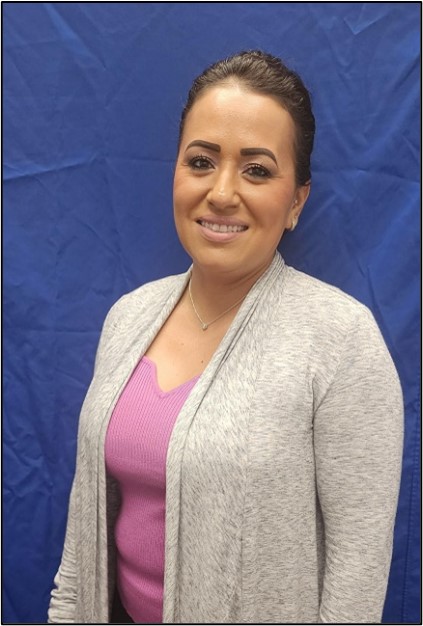 A smiling woman standing in front of a blue background.